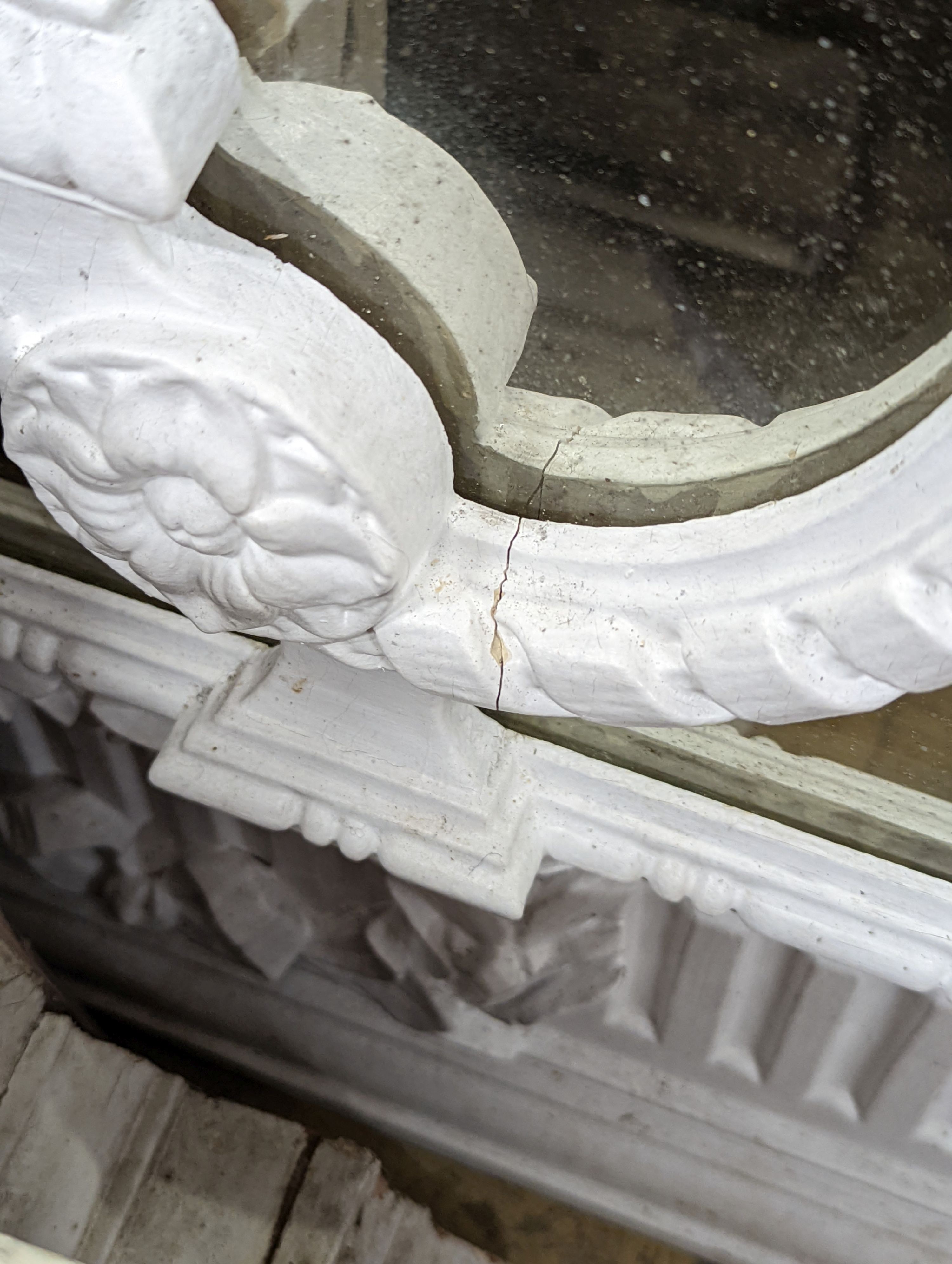 An Edwardian carved wood and gesso overmantel with cherub surmount, later painted white, width 188cm, height 96cm and a two white painted door pediments in need of restoration